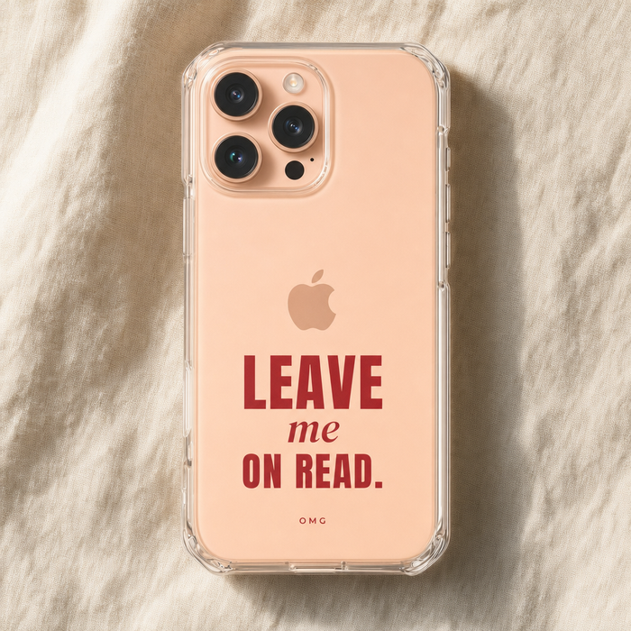 Clear iPhone case printed “Leave me on read.” in deep red, on a peach iPhone lying on cream linen
