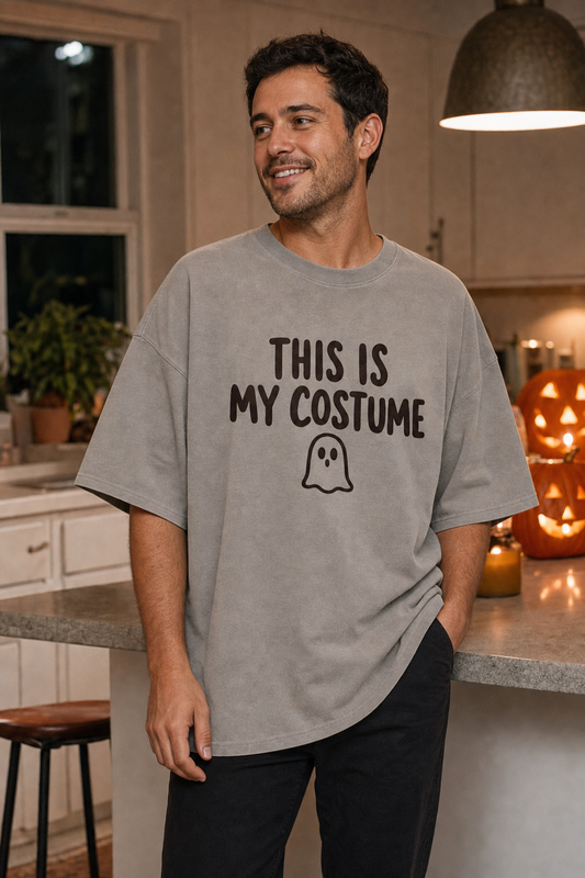 Man wearing the This Is My Costume oversized tee in Faded Grey, boxy dropped-shoulder fit, in a Halloween-lit kitchen